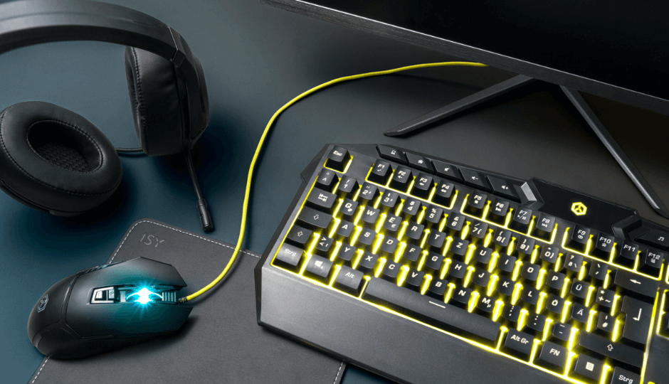 A computer mouse, mousepad, headphones, keyboard and screen, all ISY gaming products, in bleed, close-up, dark background